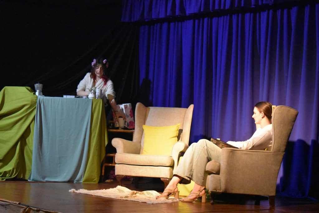 A quiet scene from Top Girls with an actor seated in an armchair