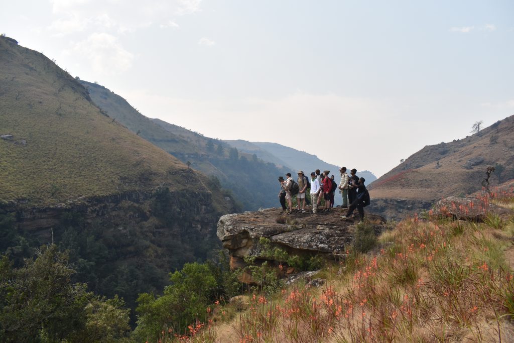 Class 11 hikers resting on a rocky outcrop above a valley