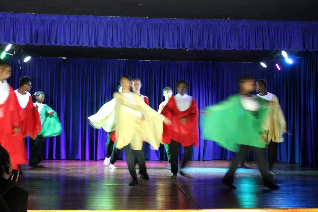 High School students in coloured silks moving across the stage in a eurythmy performance