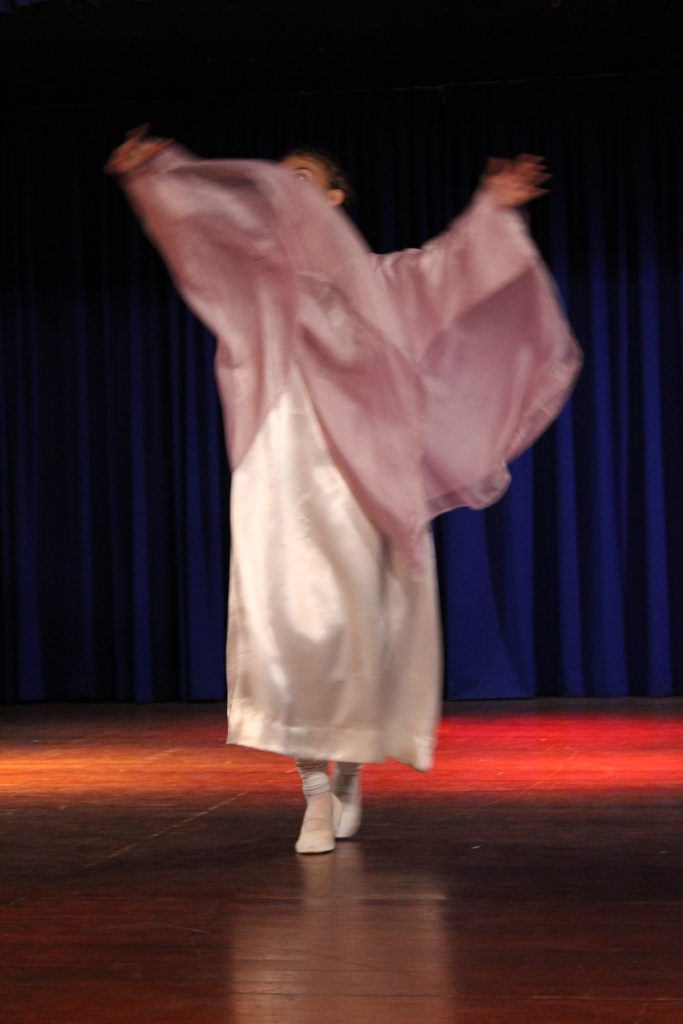 A eurythmist in a flowing pink robe on stage