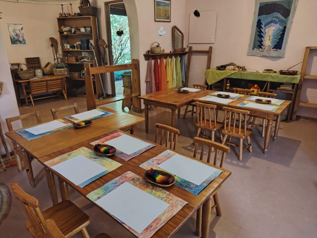The Kindergarten classroom with small wooden tables set with paper and block crayons