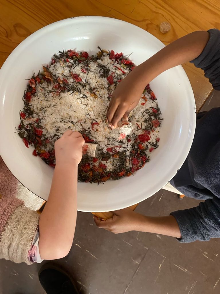 Children's hands mixing dried herbs and petals into salt