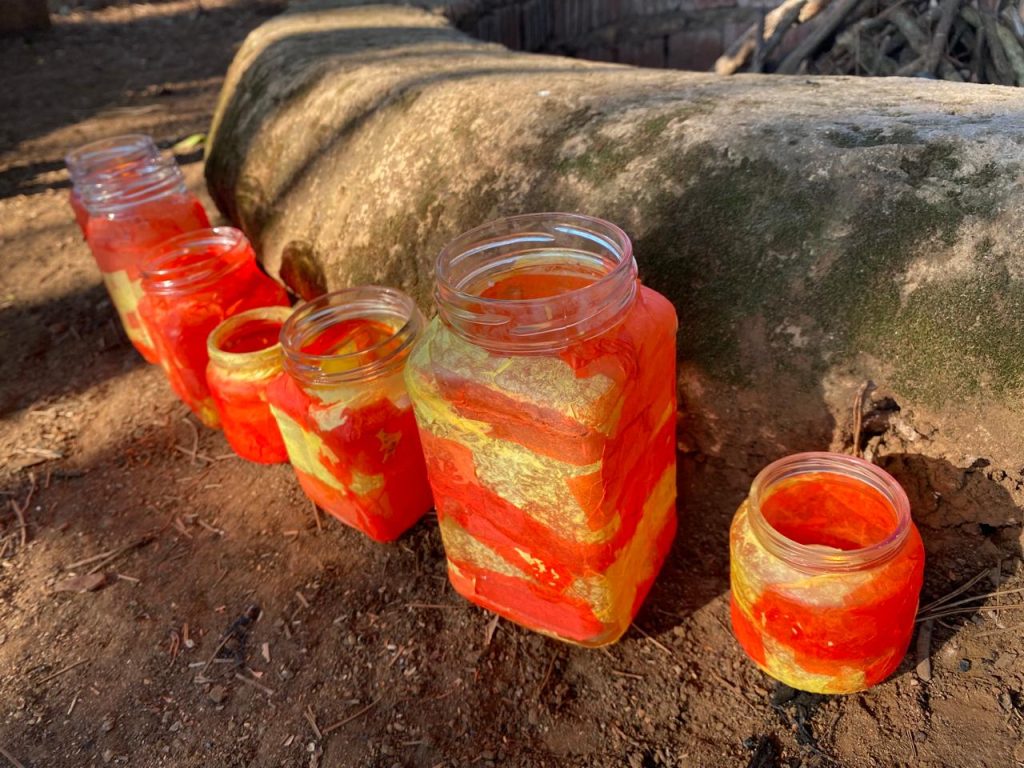 Painted glass jar lanterns glowing on the ground