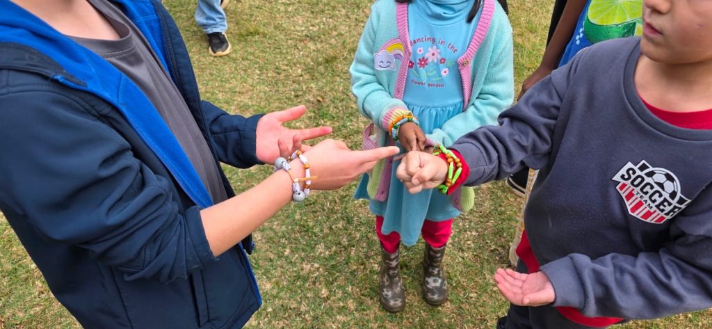 Hands playing Rock, Paper, Scissors, with friendship bracelets